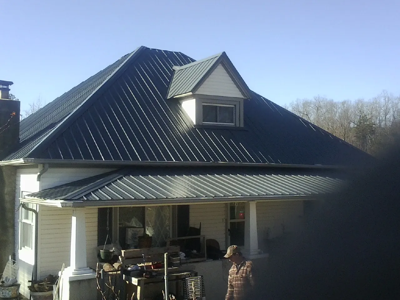 Dark blue standing seam metal roof with a dormer above a front porch in Colebrook