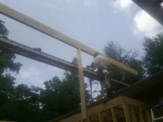 Carpenter setting a ridge beam over a new addition frame — Ice Dam Removal by Roofing Brothers in Colebrook