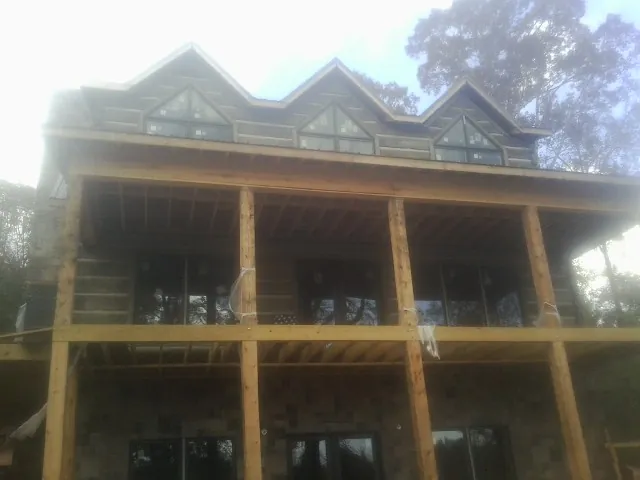 Dormers and porch framing on a large log home under construction — Roof Coating work by our crew in Colebrook