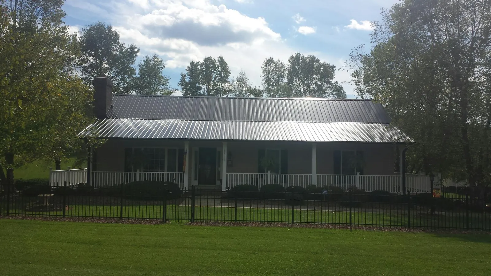 Gray metal roof on a brick ranch with a full width front porch — Gutter Guard Installation work by our crew in Colebrook
