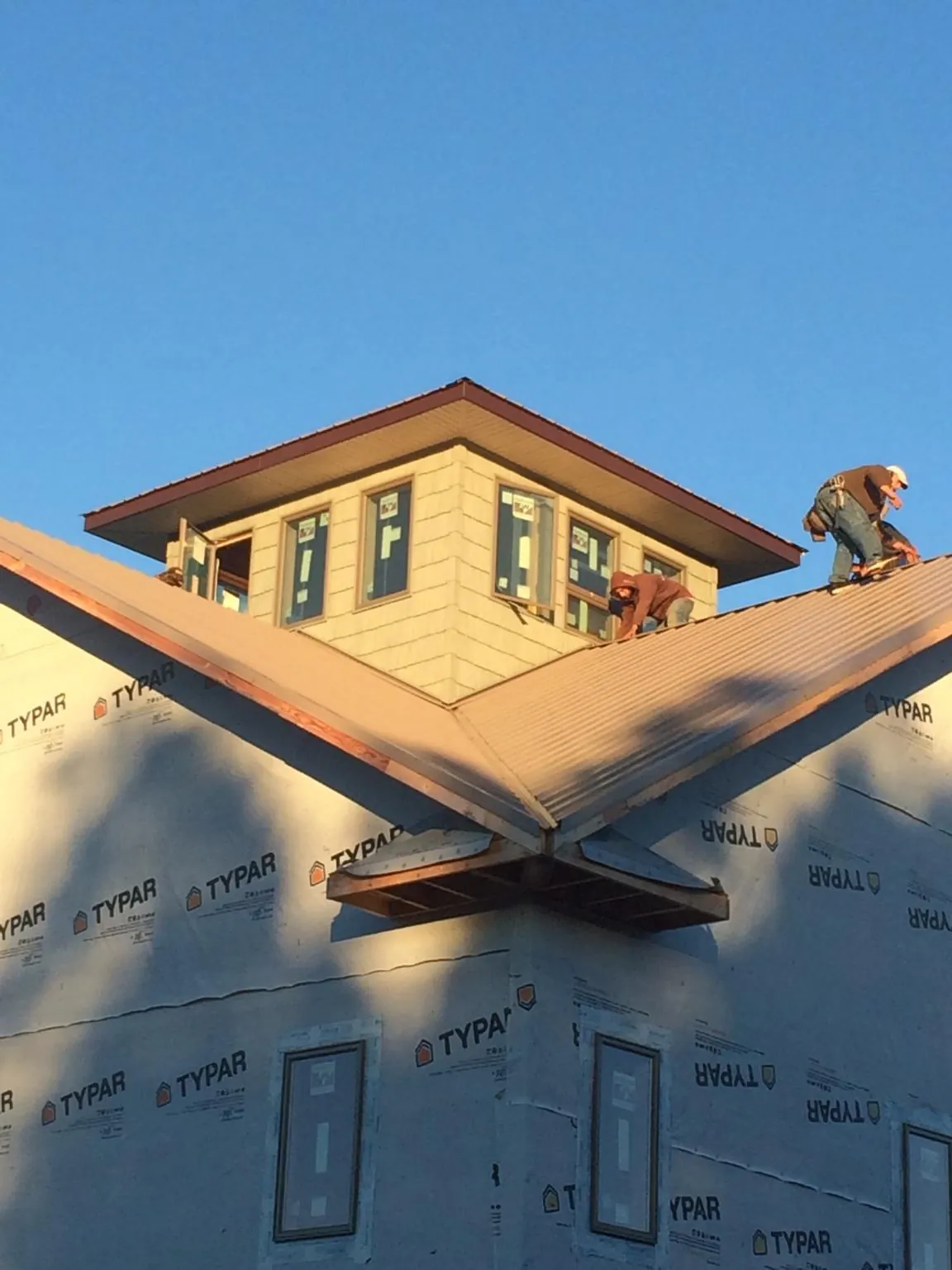 Roofers working around a rooftop cupola on a new metal roof at sunset — Roof Waterproofing in Colebrook by Roofing Brothers